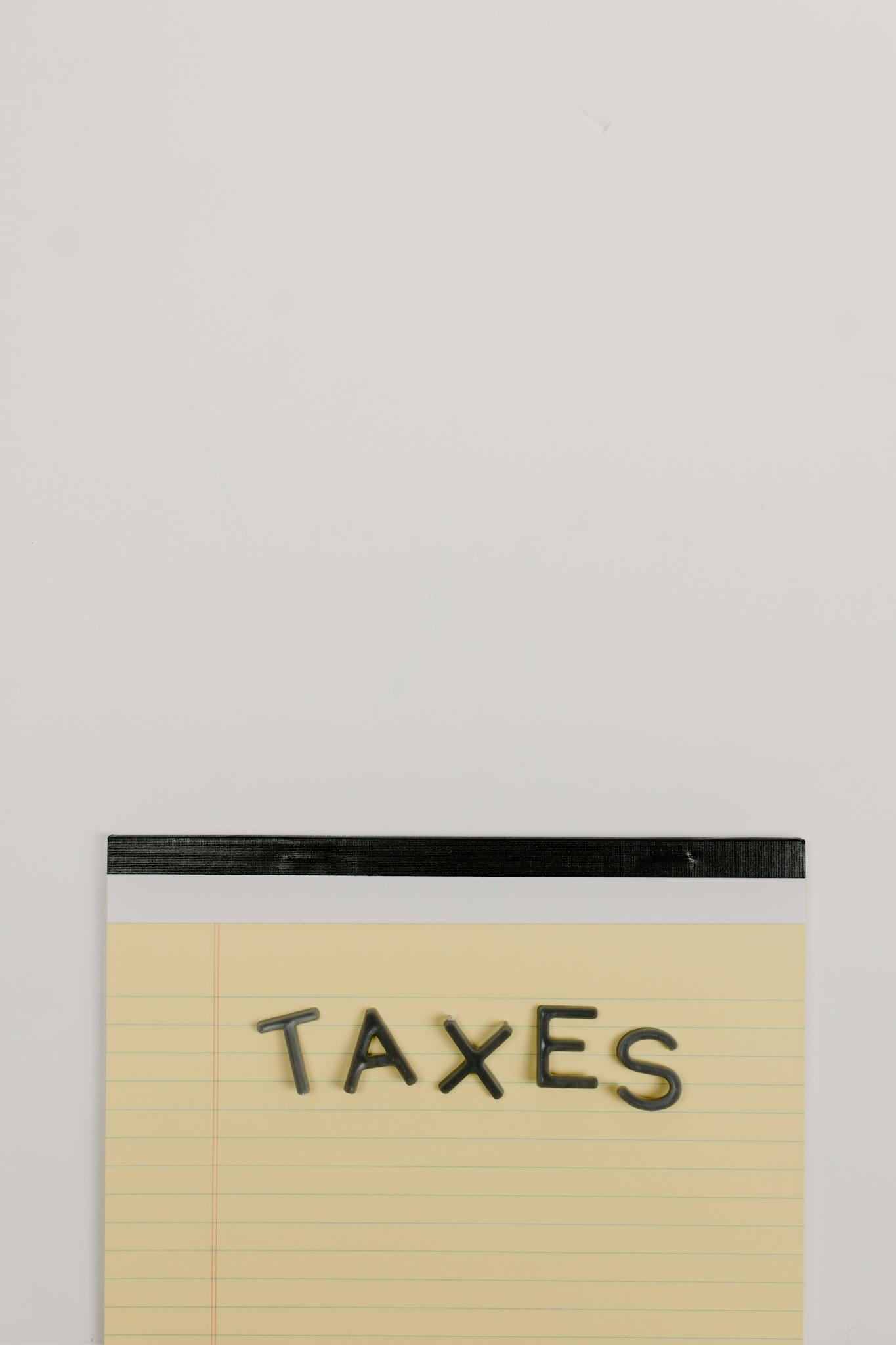 Notepad with the word 'Taxes' on a white background, ideal for finance themes.